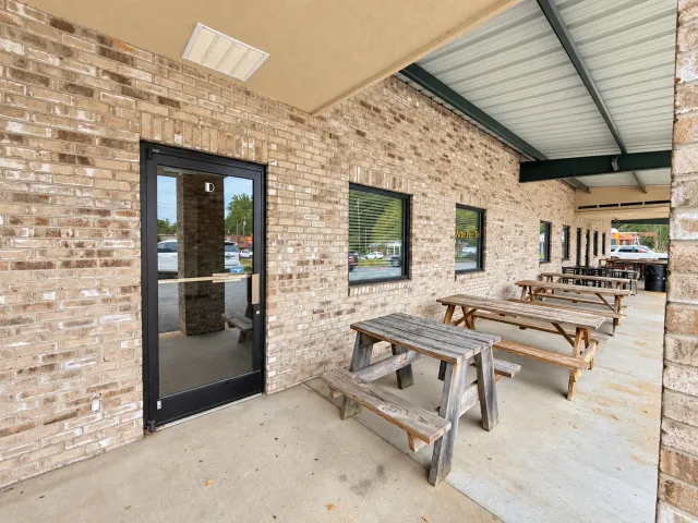 Glass storefront entrance and covered walkway with picnic tables